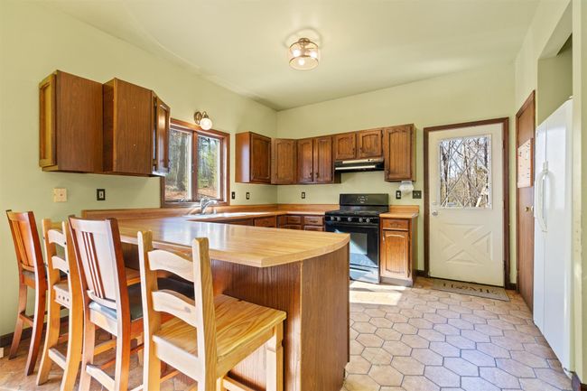 Kitchen with breakfast bar, gas stove, access to side deck and lots of natural light. | Image 8
