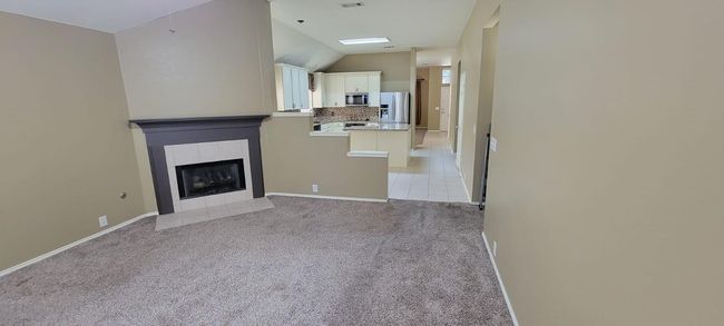 Unfurnished living room featuring light carpet, a tile fireplace, and lofted ceiling | Image 4