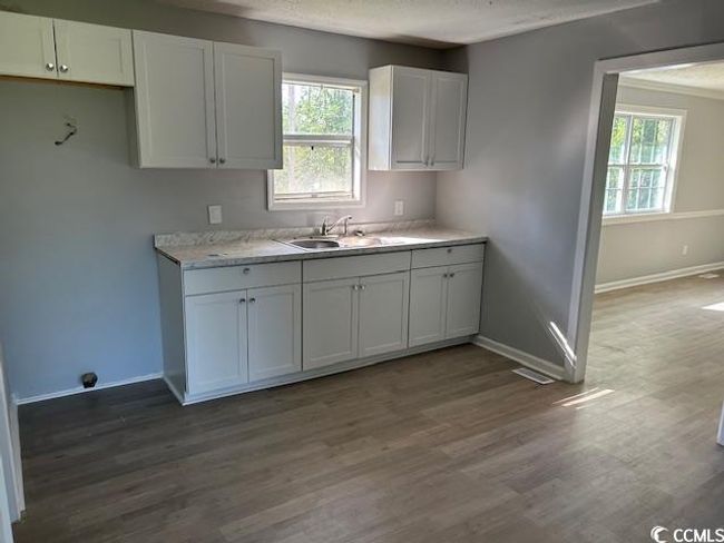 Kitchen with white cabinets, light countertops, baseboards, wood finished floors, and a sink | Image 16