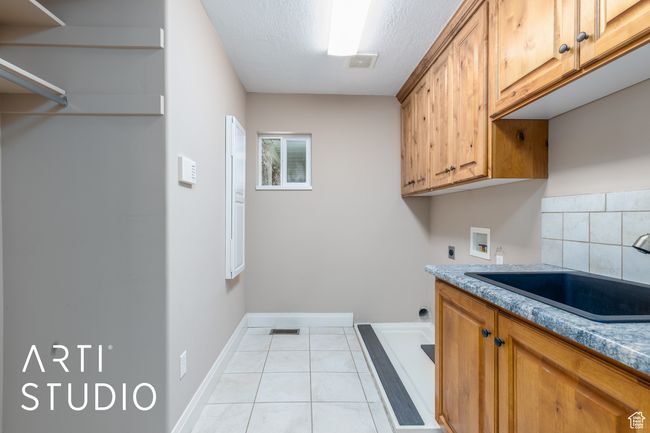 Clothes washing area featuring baseboards, light tile patterned floors, hookup for a washing machine, cabinet space, and a sink | Image 30
