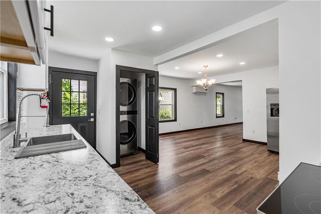 Kitchen featuring stacked washer / drying machine, a sink, a chandelier, stainless steel refrigerator with ice dispenser, and plenty of natural light | Image 22