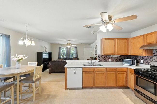 Kitchen with ceiling fan, appliances with stainless steel finishes, light countertops, open floor plan, and tasteful backsplash | Image 29