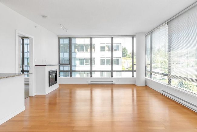 Unfurnished living room with a glass covered fireplace, a baseboard heating unit, light wood finished floors, and baseboard heating | Image 10
