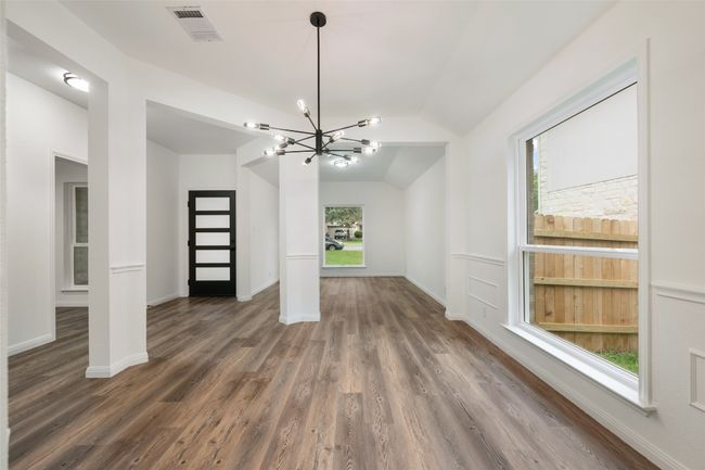 Unfurnished living room with lofted ceiling, a chandelier, and wood finished floors | Image 9