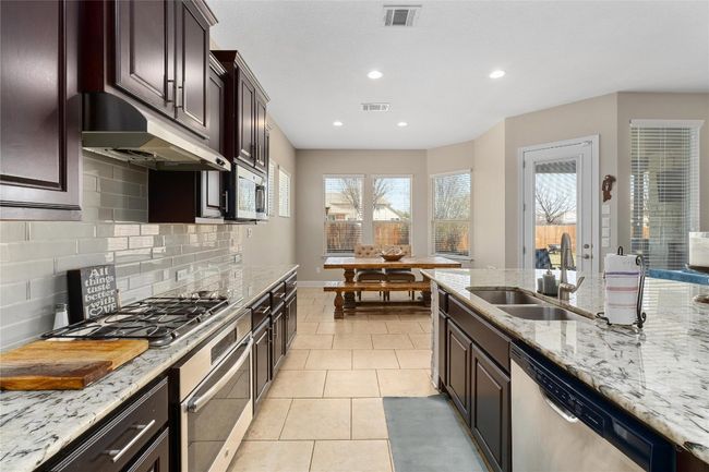 Kitchen with light tile patterned flooring, visible vents, a sink, and stainless steel appliances | Image 10