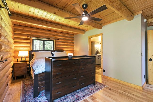 Master Bedroom featuring wooden ceiling with exposed beams, light wood finished floors, log walls, ensuite bathroom, and baseboards | Image 20