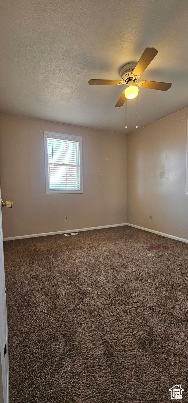 Unfurnished room with ceiling fan, dark carpet, and a textured ceiling | Image 32