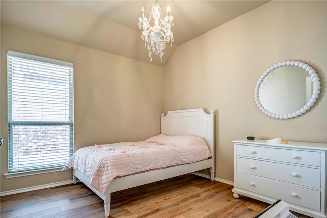 Bedroom featuring baseboards, light wood-type flooring, a notable chandelier, and lofted ceiling | Image 33