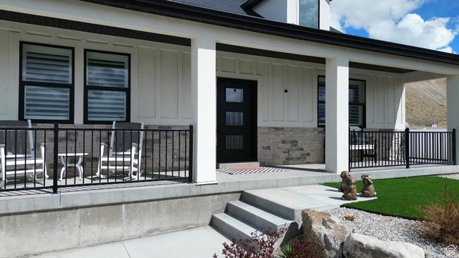 View of exterior entry with covered porch, stone siding, and board and batten siding | Image 78
