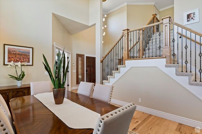Dining room featuring crown molding, stairs, wood finished floors, baseboards, and a high ceiling | Image 8
