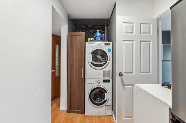 Laundry room with stacked washer / dryer, laundry area, and light wood-style floors | Image 30