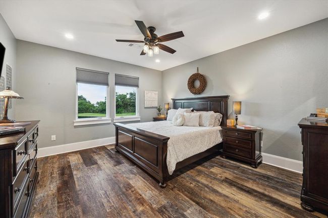 This serene upstairs bedroom offers stunning views of the back pond, creating a peaceful retreat. It includes a private bathroom for ultimate convenience and privacy, along with a laundry room chute for easy access to the laundry room below. The spacious walk-in closet provides plenty of storage, while the oversized shower with a sleek sliding glass door adds a touch of luxury. A perfect blend of comfort and practicality! | Image 27