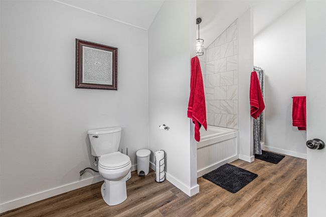 Full bathroom with wood finished floors, vaulted ceiling, and shower / tub combo | Image 22