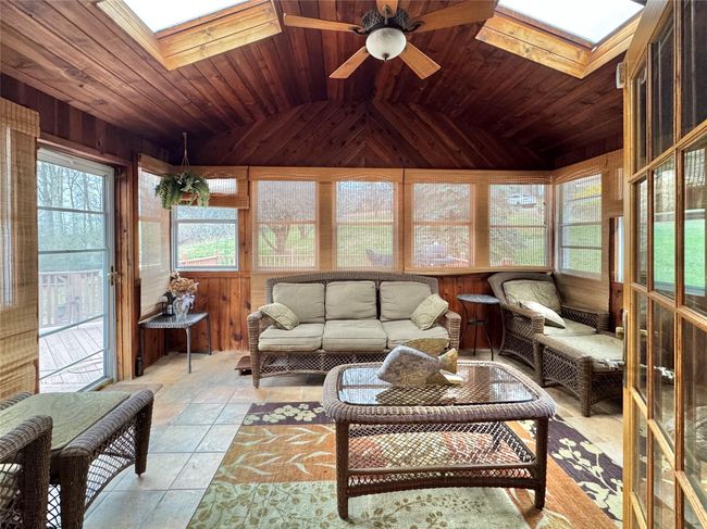 Sunroom / solarium with wood walls, plenty of natural light, wood ceiling, and ceiling fan | Image 12