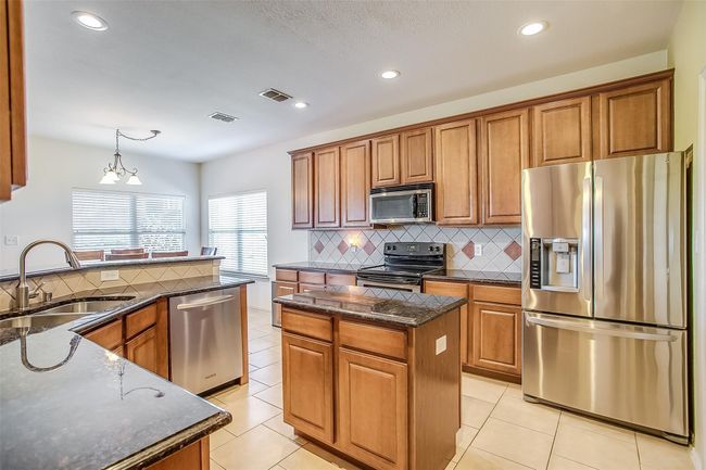 Kitchen featuring deep double sink, lots of cabinetry, stainless steel appliances, and an island with storage. | Image 10