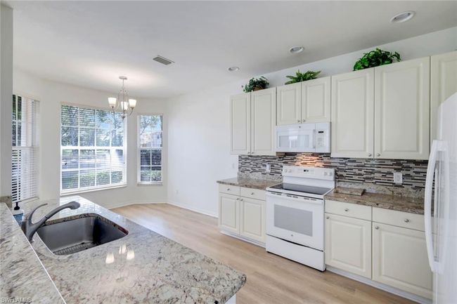 Kitchen, with eat-in kitchenette, light wood-style floors, backsplash, and white appliances | Image 7