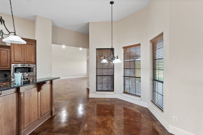 Kitchen featuring stainless steel microwave, a high ceiling, dark countertops, baseboards, and pendant lighting | Image 9
