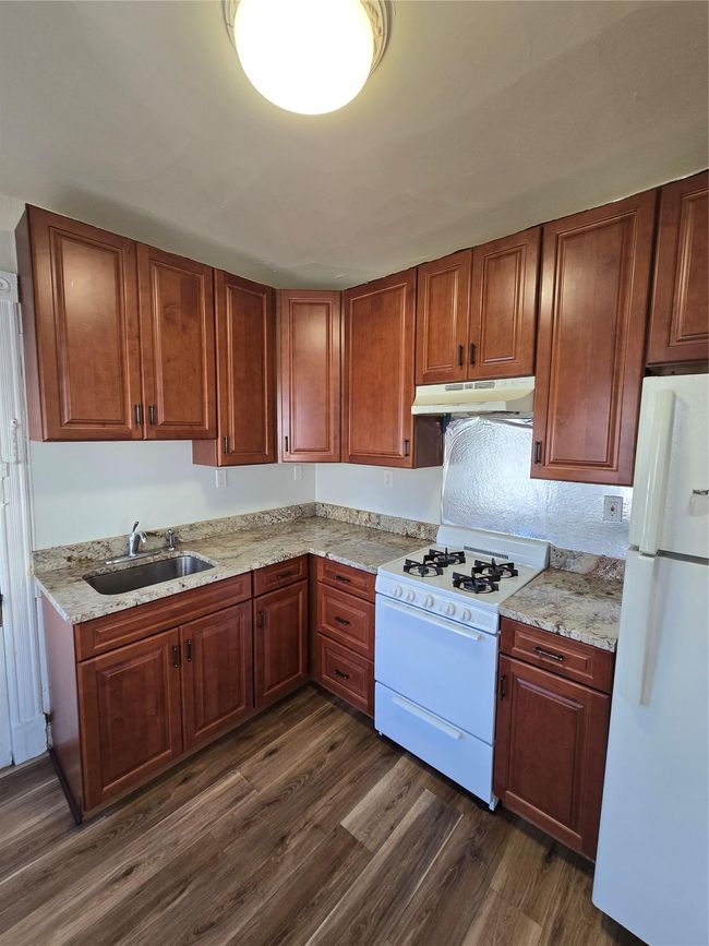 Kitchen featuring refrigerator, range, extractor fan, a sink, and dark wood-style flooring | Image 5