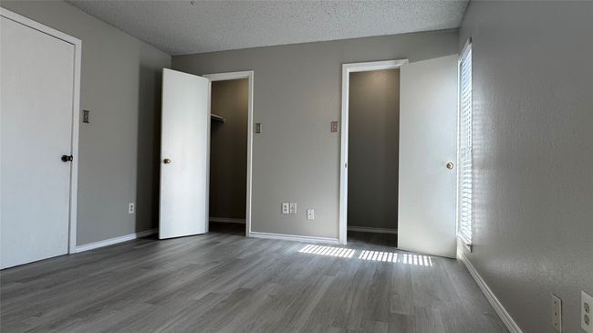 Unfurnished bedroom with wood finished floors, a textured ceiling, and baseboards | Image 11