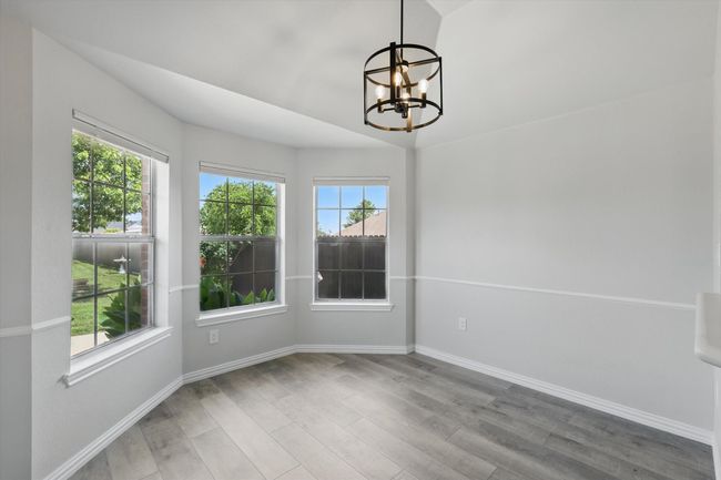 Unfurnished dining area with a chandelier, wood finished floors, plenty of natural light, and baseboards | Image 9
