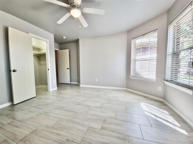 Unfurnished bedroom featuring multiple windows, a ceiling fan, and a walk in closet | Image 11