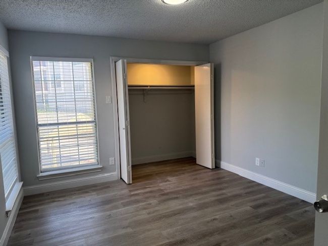 Unfurnished bedroom with dark wood-type flooring, multiple windows, a textured ceiling, and a closet | Image 14