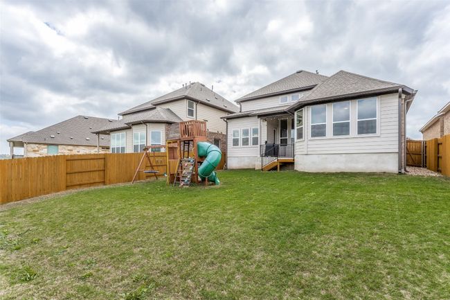 Back of property featuring a playground, a fenced backyard, and roof with shingles | Image 20