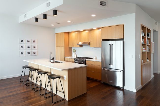 Kitchen featuring under cabinet range hood, visible vents, a sink, high quality appliances, and a breakfast bar area | Image 8