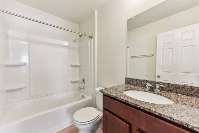 Bathroom with shower / bathing tub combination, toilet, tile patterned flooring, and vanity | Image 28