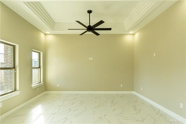 Spare room featuring baseboards, marble finish floor, a tray ceiling, crown molding, and recessed lighting | Image 12