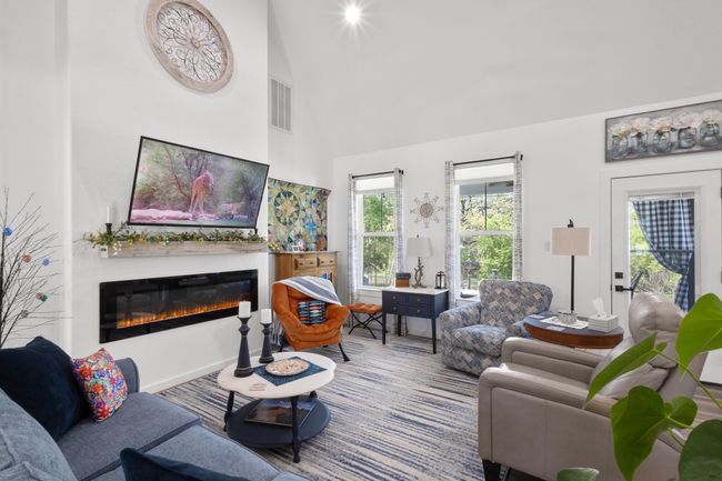 Living room with a glass covered fireplace, visible vents, and a high ceiling | Image 8