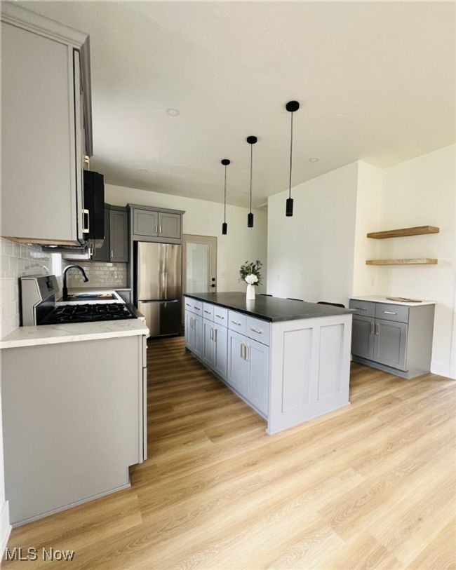 Kitchen featuring tasteful backsplash, open shelves, appliances with stainless steel finishes, light wood-style floors, and gray cabinetry | Image 8