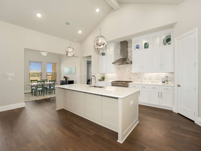 The kitchen is a culinary masterpiece, featuring an expansive island perfect for entertaining, quartz countertops, sleek white cabinetry with glass display fronts, an apron-front farm sink, and high-end stainless-steel appliances, including a six-burner gas cooktop and double convection oven. | Image 8