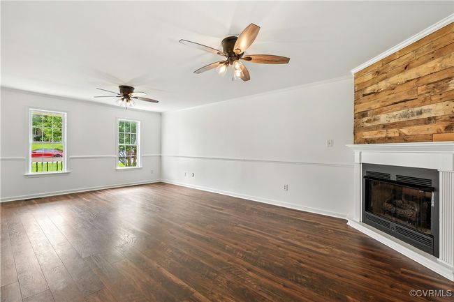 Another view with ceiling fan, a fireplace, Laminate wood-style flooring, and ornamental molding | Image 7