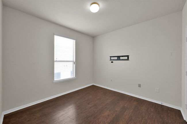This room features hardwood flooring, neutral walls, and a ceiling light. It includes a double-door closet and additional door access, offering a simple and versatile space. | Image 22