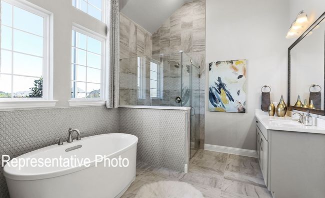 Full bathroom with a stall shower, a freestanding tub, vanity, lofted ceiling, and marble finish floors | Image 7