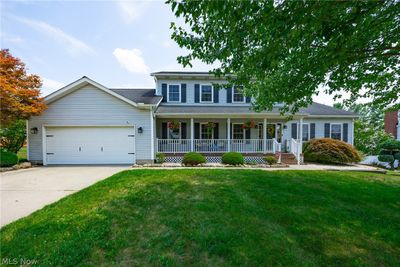 Colonial-style house with a garage, a porch, and a front yard | Image 1