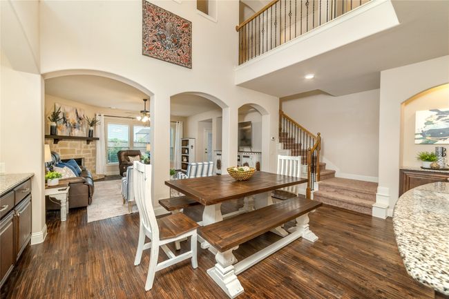 Dining space with dark wood-style flooring, stairs, a ceiling fan, baseboards, and a high ceiling | Image 8
