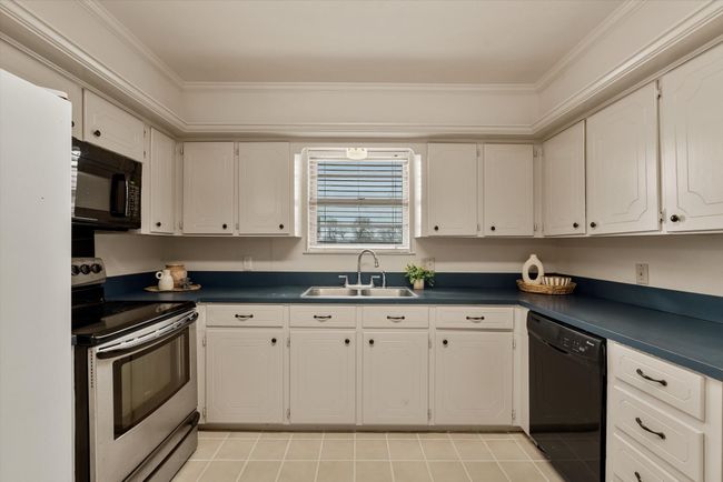Kitchen with white cabinets, ornamental molding, sink, and black appliances | Image 14