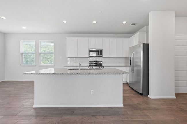 Kitchen with appliances with stainless steel finishes, light stone countertops, decorative backsplash, an island with sink, and recessed lighting | Image 8