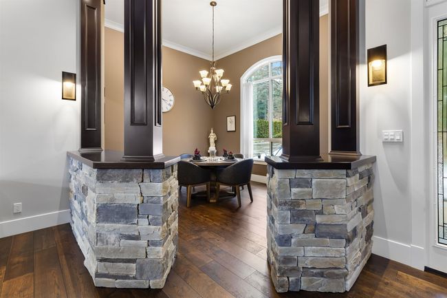 Interior space with a chandelier, dark wood-style flooring, baseboards, decorative light fixtures, and crown molding | Image 8