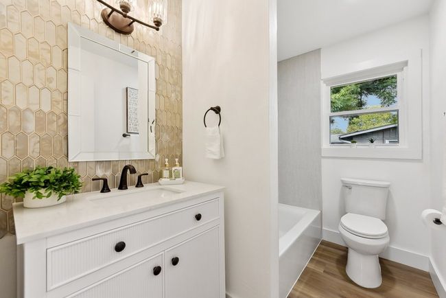 Full bath featuring vanity, wood finished floors, baseboards, toilet, and a washtub | Image 15