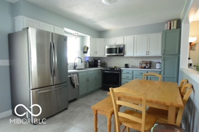 kitchen with backsplash, white cabinetry, stainless steel appliances, and a sink | Image 27