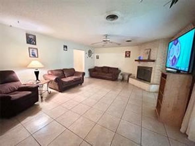 Living room with light tile patterned floors, ceiling fan, and a brick fireplace | Image 5