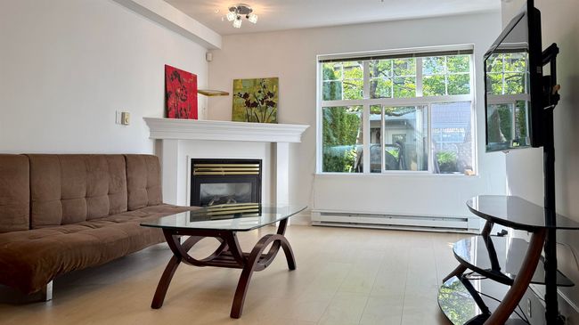 Living room with baseboard heating, healthy amount of natural light, and a glass covered fireplace | Image 6