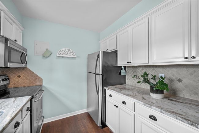 Kitchen with appliances with stainless steel finishes, dark wood finished floors, light stone countertops, and backsplash | Image 15
