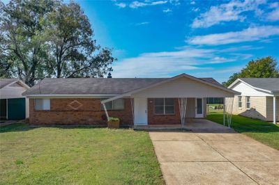 Ranch-style home with a front lawn and a carport | Image 1