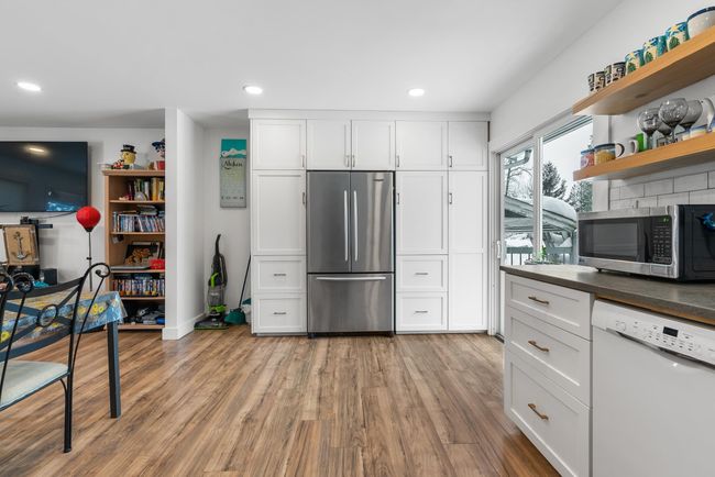 Kitchen with open shelves, appliances with stainless steel finishes, wood finished floors, and white cabinetry | Image 16
