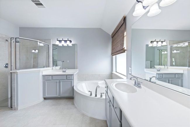 The primary bathroom offers a clean, airy feel with dual vanities, a large soaking tub, and a separate glass-enclosed shower. | Image 15