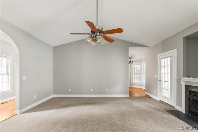 Unfurnished living room featuring carpet flooring, vaulted ceiling, a high end fireplace, ceiling fan, and arched walkways | Image 7